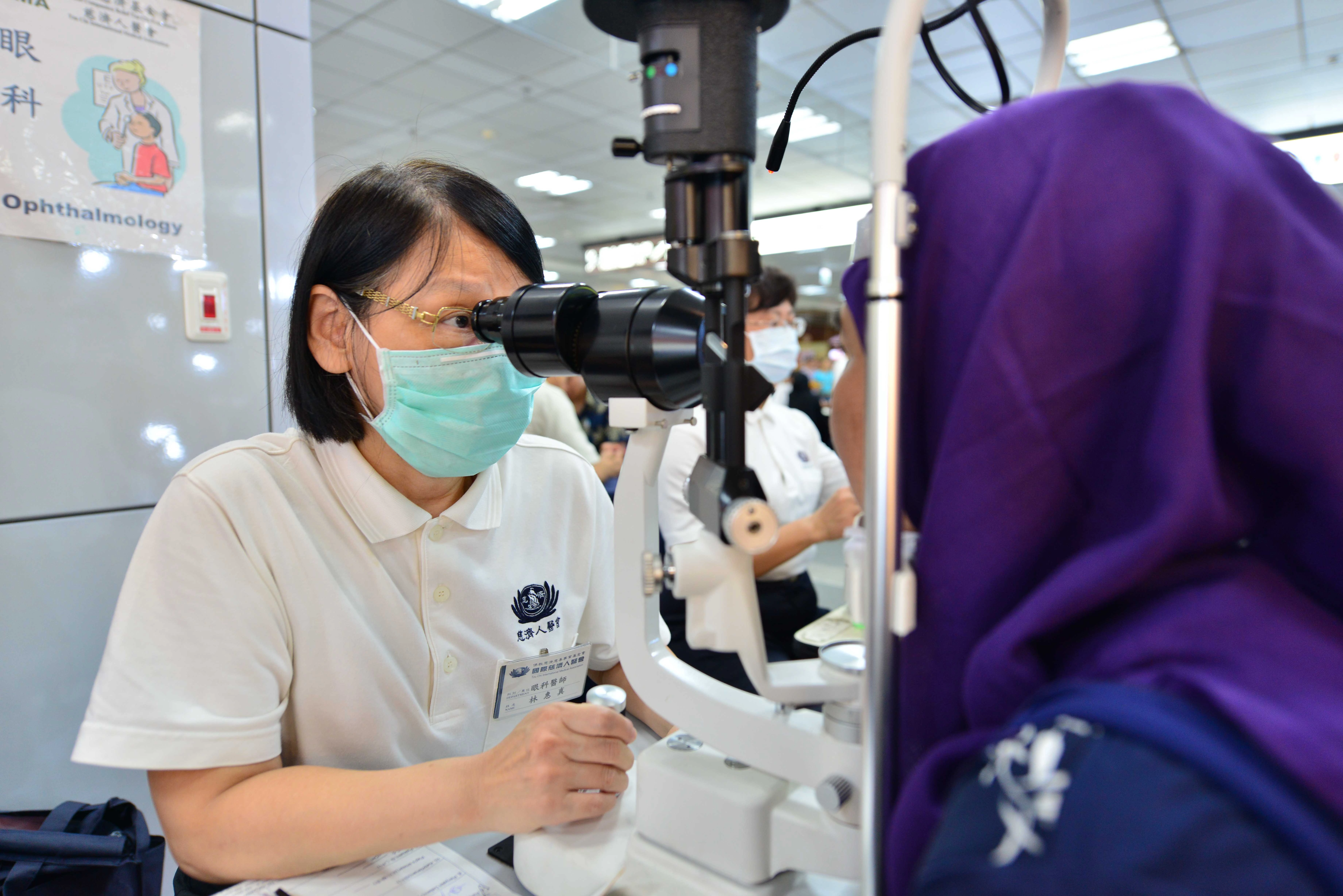 眼科林惠真醫師（左）仔細地幫外籍移工檢測 眼睛並叮嚀眼睛保養的觀念。