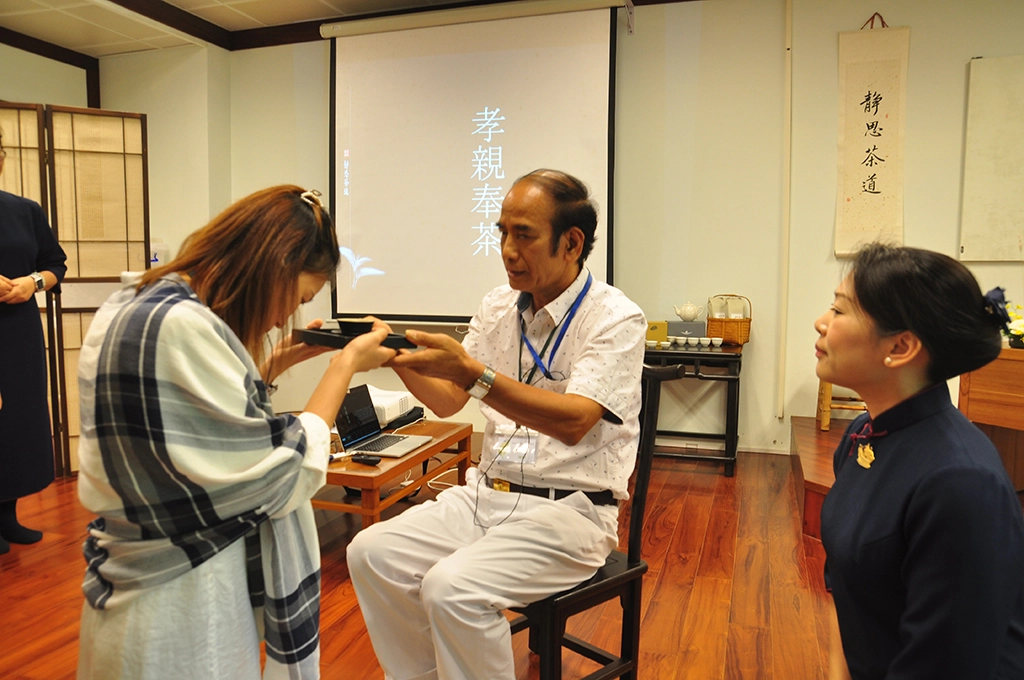 學員們學習奉茶禮儀的「三心」:感恩心（端捧茶盤）、尊重心（敬上茶盞）與愛心（微笑颌首）。