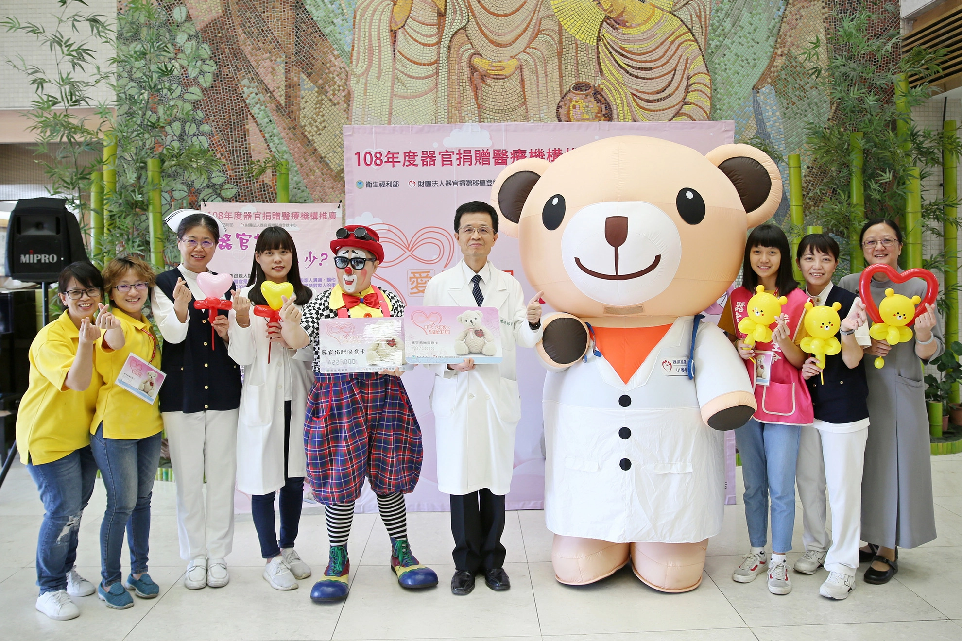 花蓮慈濟醫院副院長陳培榕(右五)與小麥貝兒熊（右四）、小丑熊熊（左五）及器捐宣導團隊邀約民眾一起來簽署器官捐贈同意書。