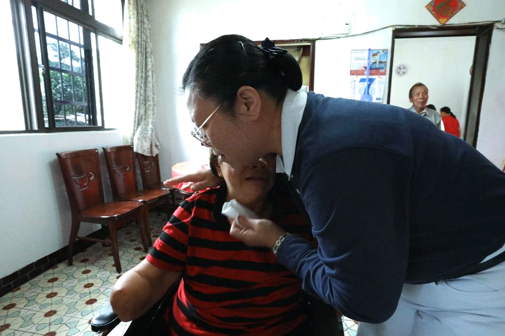 雙手雙腳截肢的阿嬤，因為行動不便，無法前往醫院探視眼睛開刀的先生，心情焦急萬分。志工黃莉珊（右）抱抱阿嬤安慰她「要將擔憂化做祝福。」