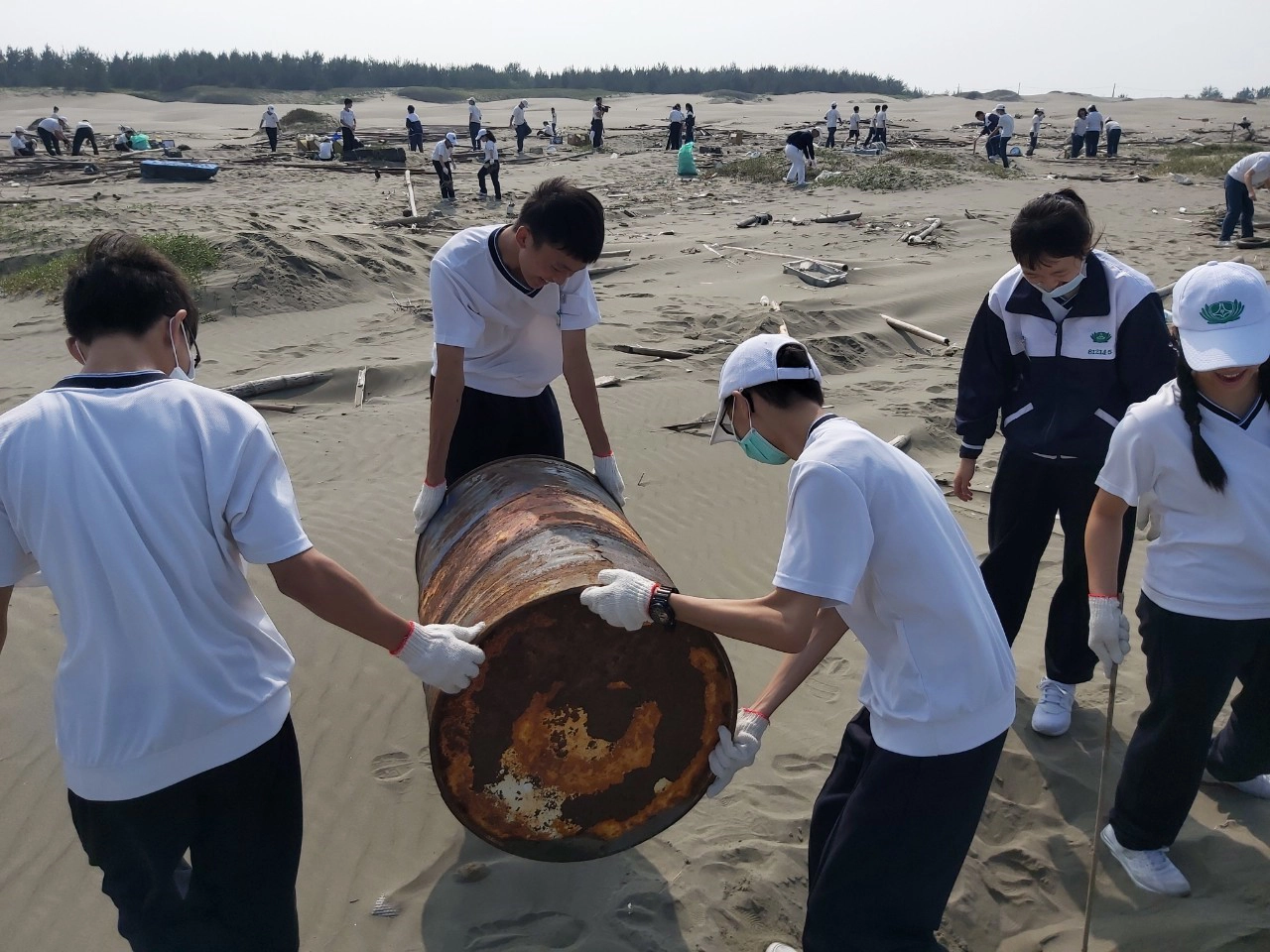 在沙灘上撿拾到從船上拋入海的大型油桶。(張宏州攝)