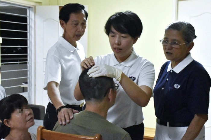 周秋麗（右二）跟隨父親周啟仕（右三）和志工參與居家往診，也為林先生提供針灸治療。