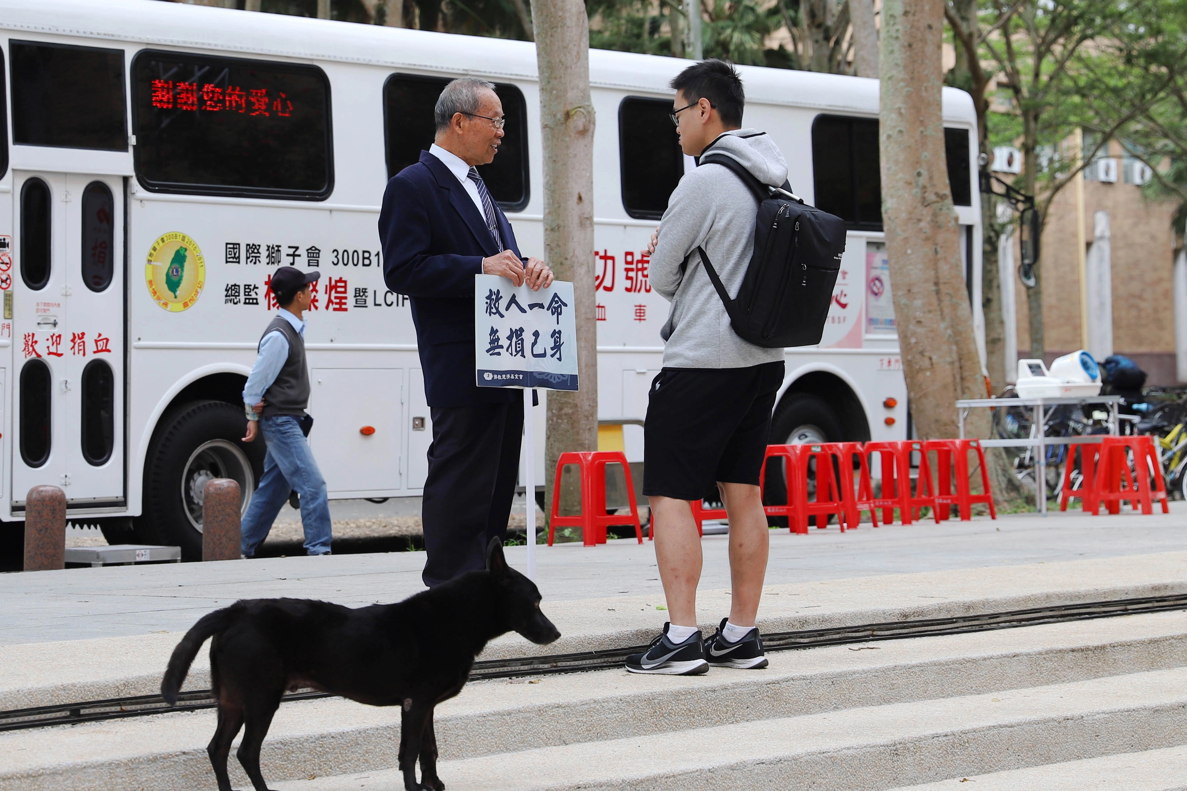 東華大學與慈濟骨髓幹細胞中心共同辦理的造血幹細胞驗血建檔活動於3日起一連三天在東華湖畔廣場辦理，志工舉牌「救人一命無損己身」，吸引不少學生前往了解。(慈濟基金會提供)