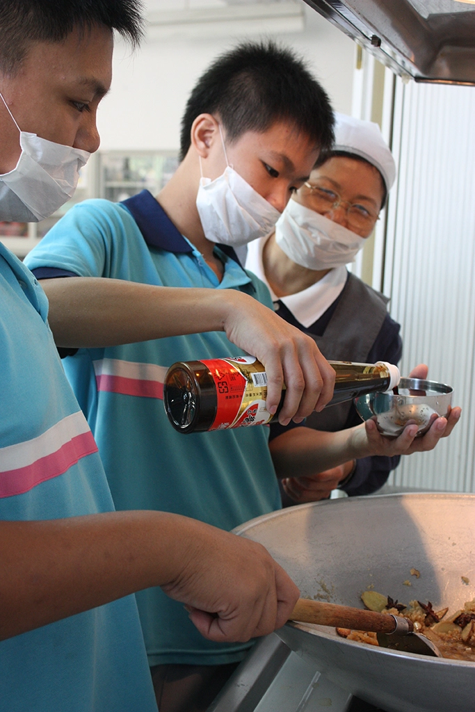 台中慈濟志工至成功國中關懷中輟生。志工林梅珠指導同學們烹煮滷豆干。