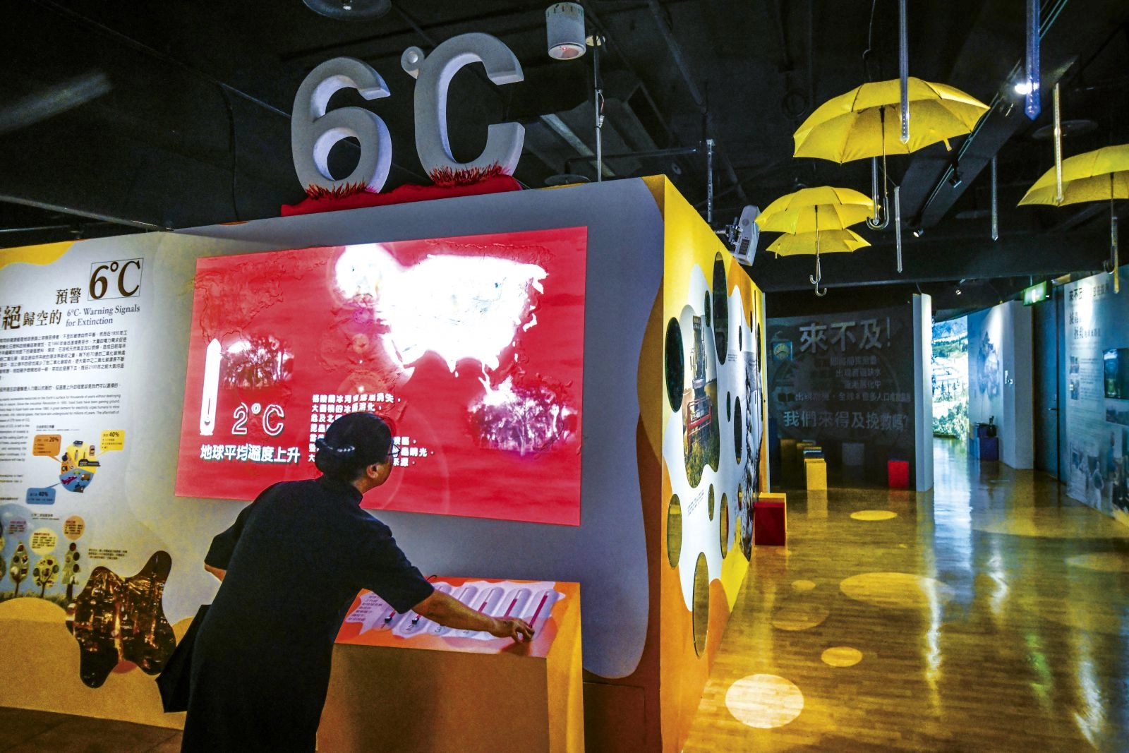 高雄靜思堂環境教育館內，負責解說的志工操作按鈕，螢幕即顯示地球暖化每升高一度所遭遇的狀況。