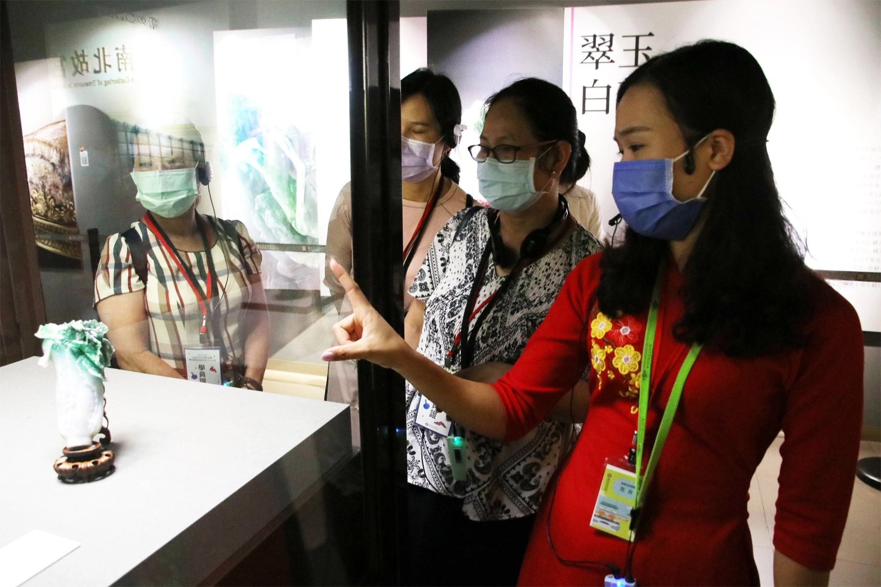 越南新住民范氏月(右1)指出翠玉白菜只有18公分高，但卻雕工精細，令人陶醉。