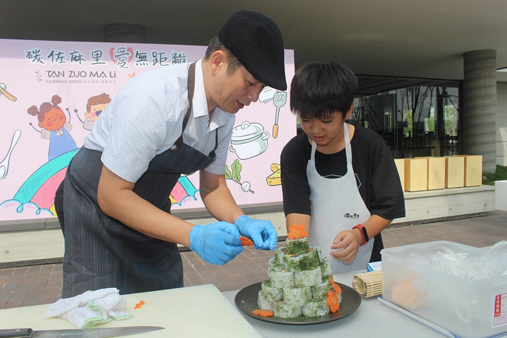 伊甸基金會象圈社區學童小恩(右)，首次參加碳佐料理小學堂活動，親手製作聖誕壽司樹。