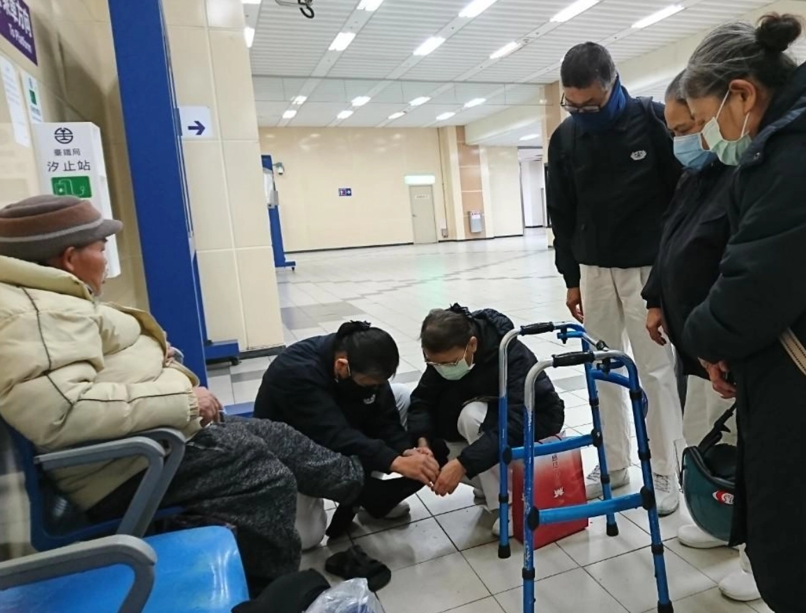 汐止慈濟志工前往汐止車站關懷街友，親自為他們穿上防寒衣物襪。