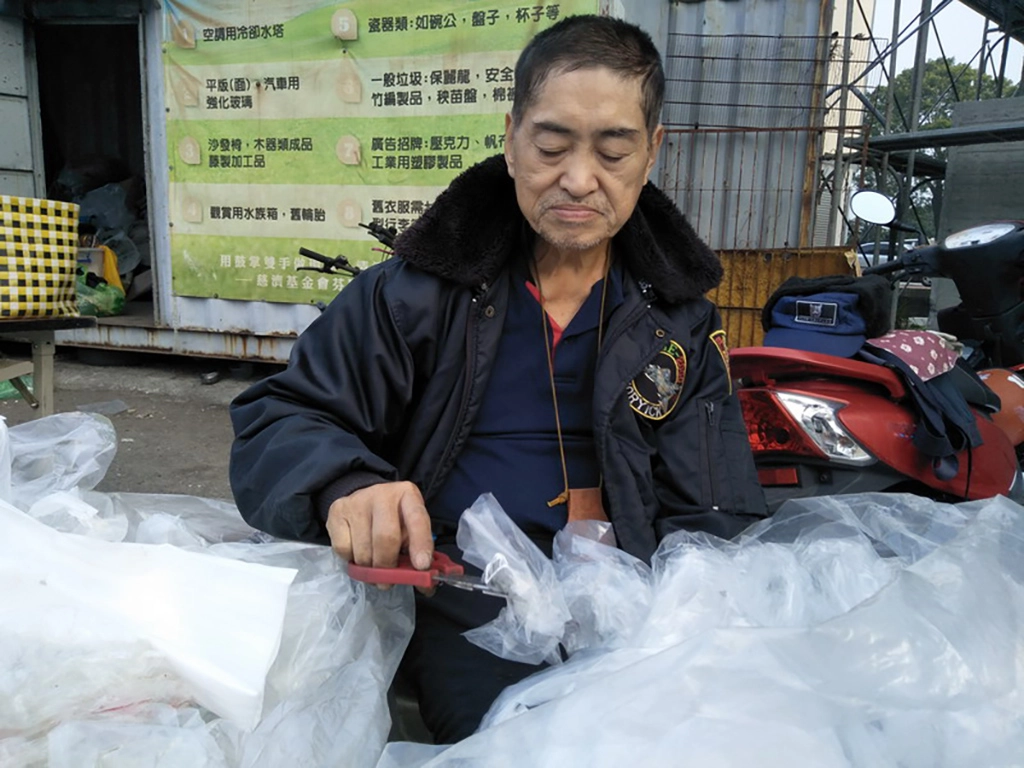 許老先生雖中風但仍能以單手持剪刀整理塑膠袋。