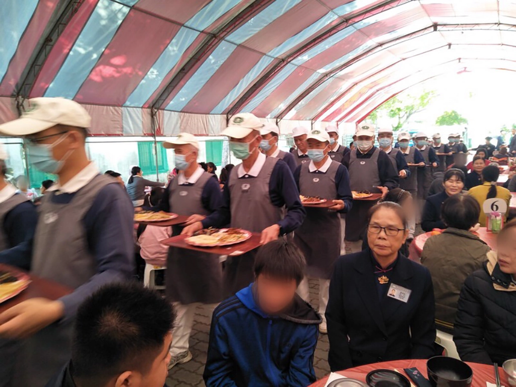 歲末圍爐現場由慈濟志工上菜秀恭敬端出美食佳餚。