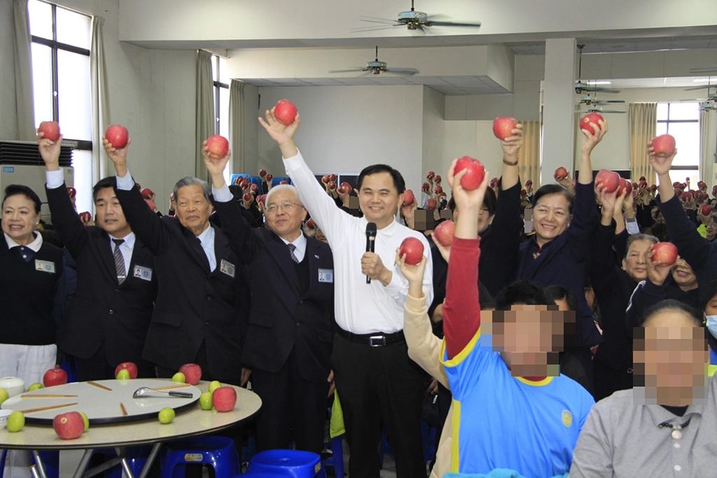 開桌之前，慈濟志工與雲嘉南區人醫會召集人簡瑞騰醫師，和所有照顧戶、關懷戶，舉起手中代表平安吉祥的超大紅蘋果，大聲祝福平安吉祥。