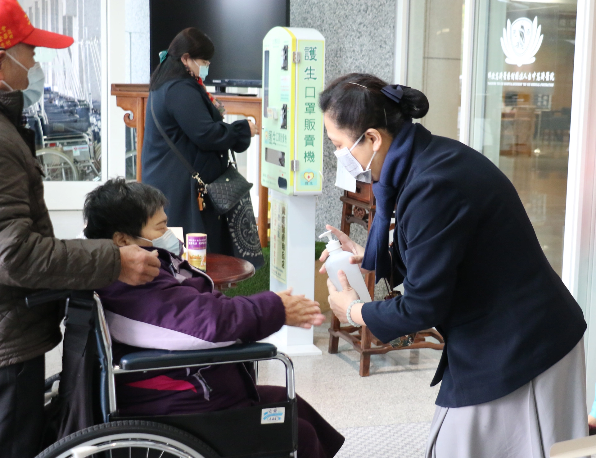 臺中慈濟醫院副院長莊淑婷（右）為訪客消毒清潔雙手。