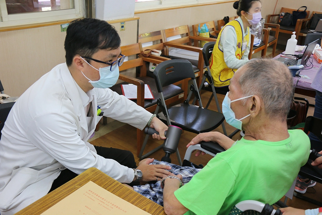 臺中慈濟醫院中醫師陳智聖 (左) 以筋膜槍為住民按摩。