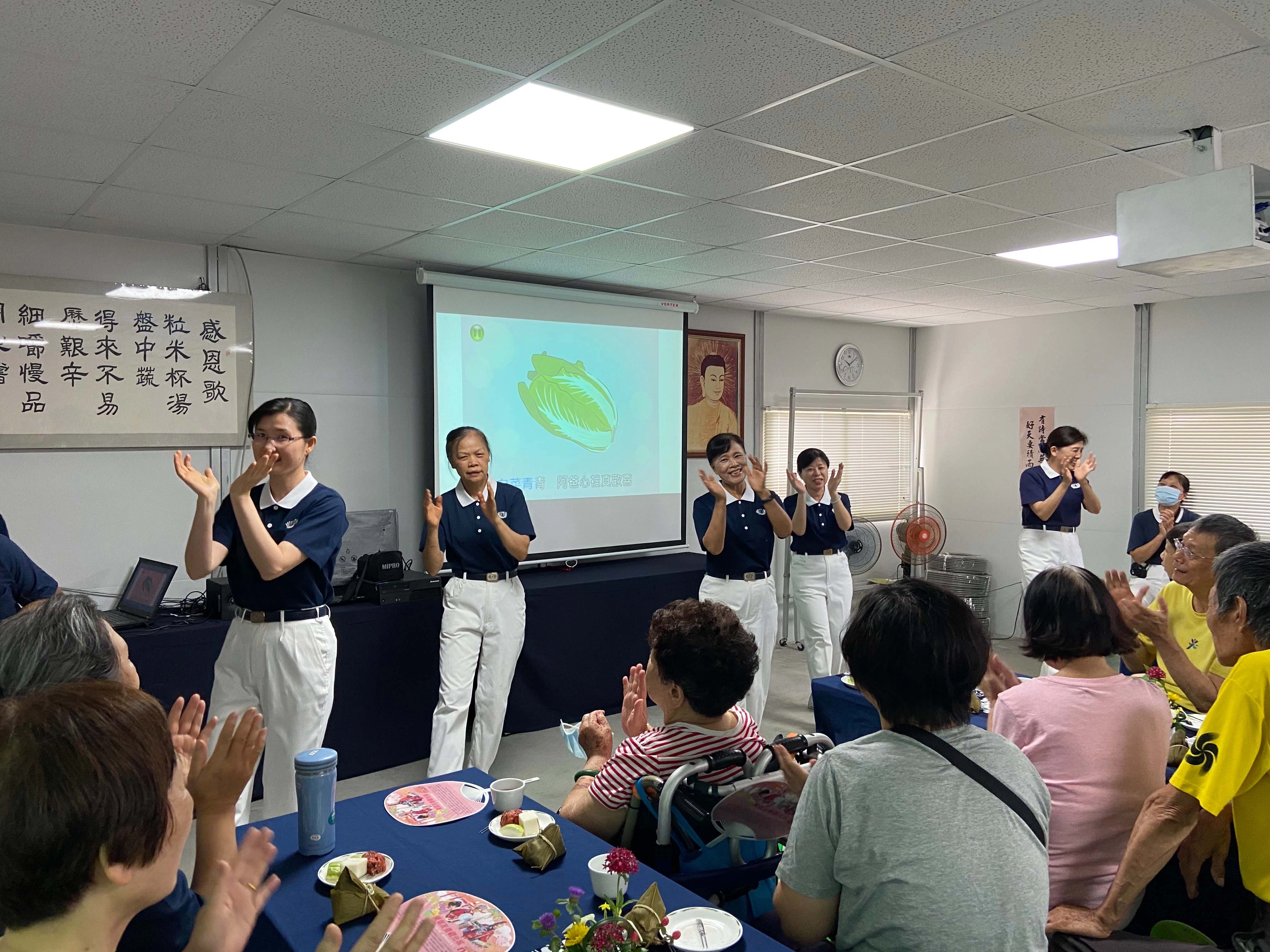 慈濟志工們用手語表演炒熱氣氛，大家跟著老師一起律動，年長者也試著在位子上活動筋骨。