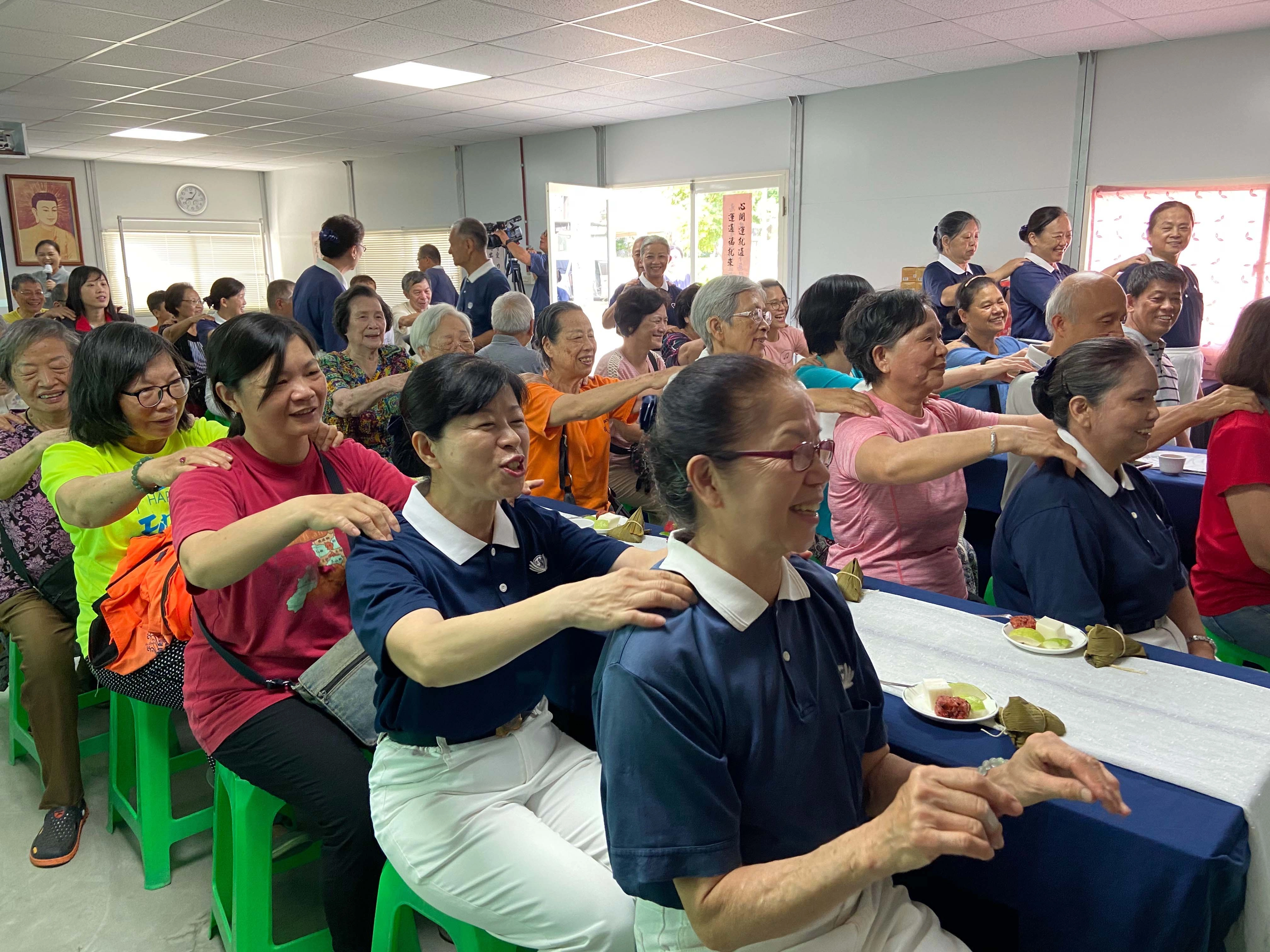 慈濟志工們用手語表演炒熱氣氛，大家跟著老師一起律動，年長者也試著在位子上活動筋骨。