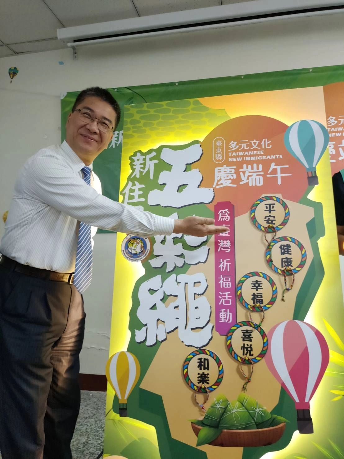 徐國勇和新住民朋友共同將親手製作的五彩繩繫在臺灣圖像看板上，祈求臺灣永保安康！
