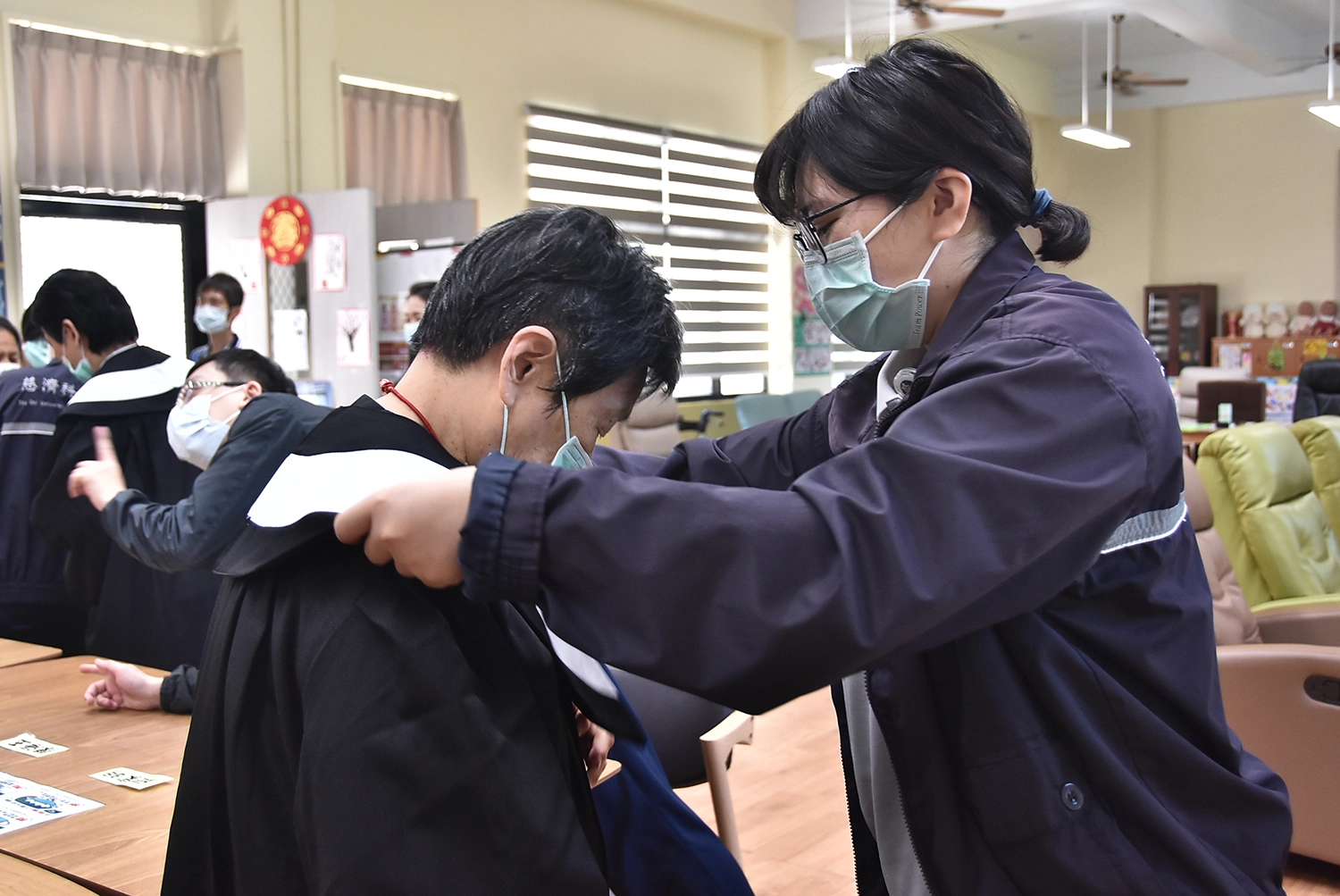 慈濟科技大學生協助長輩穿學士服。