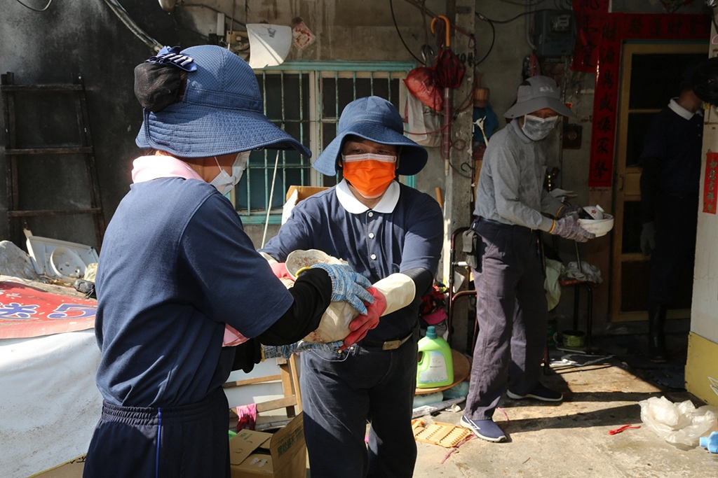 志工用接龍方式將屋內雜物搬到屋外。