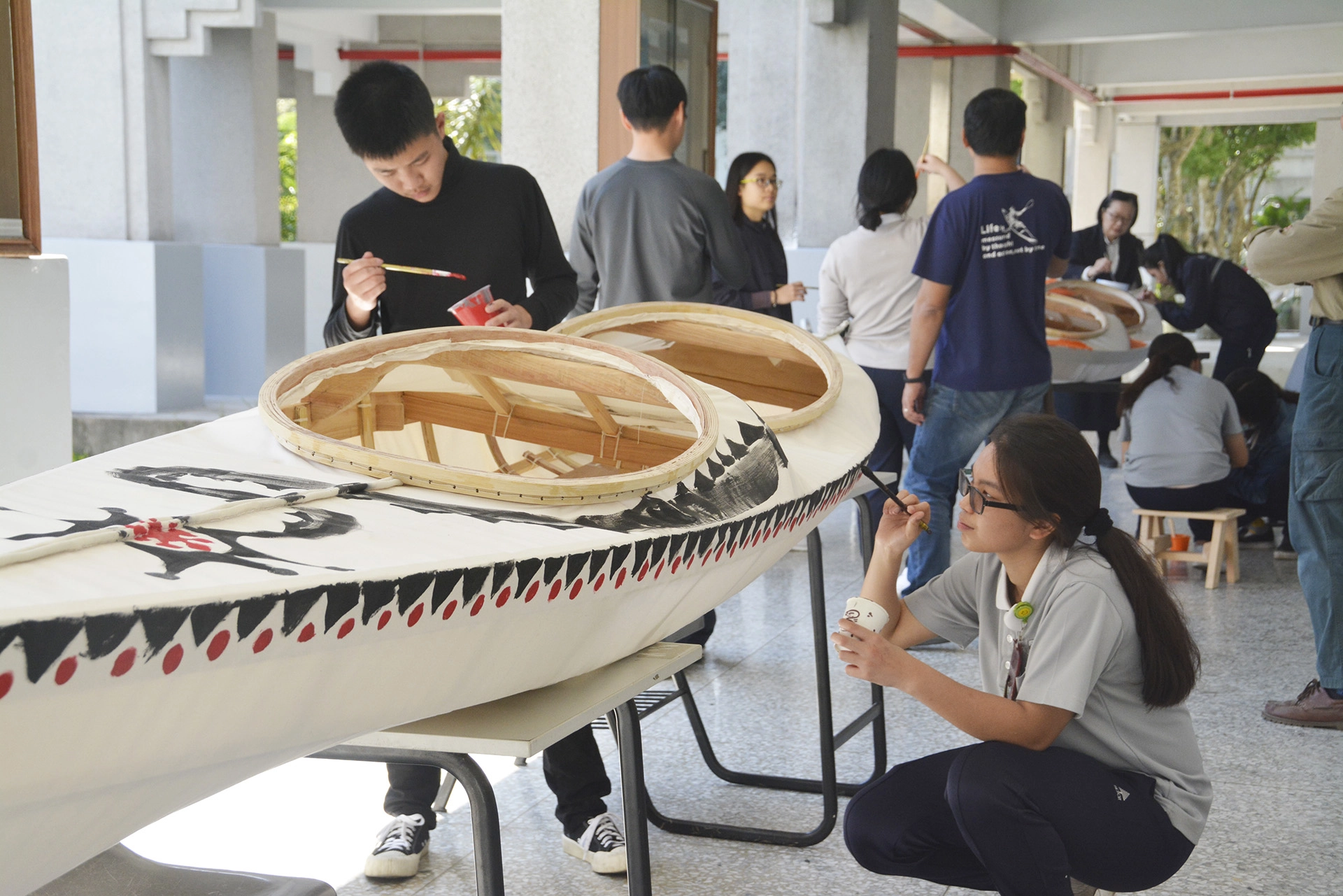 慈濟科技大學學生為親手製作的格陵蘭骨架蒙皮舟彩繪喜歡的圖案。