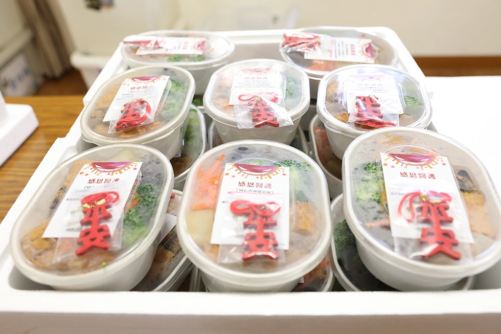 每個便當盒上黏貼的「感恩醫護」貼紙及附上的平安吊飾，祝福大家平平安安，同心共濟弭災疫。