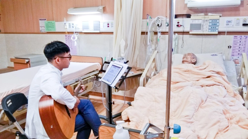 李思賢醫師在床畔為病人彈吉他。