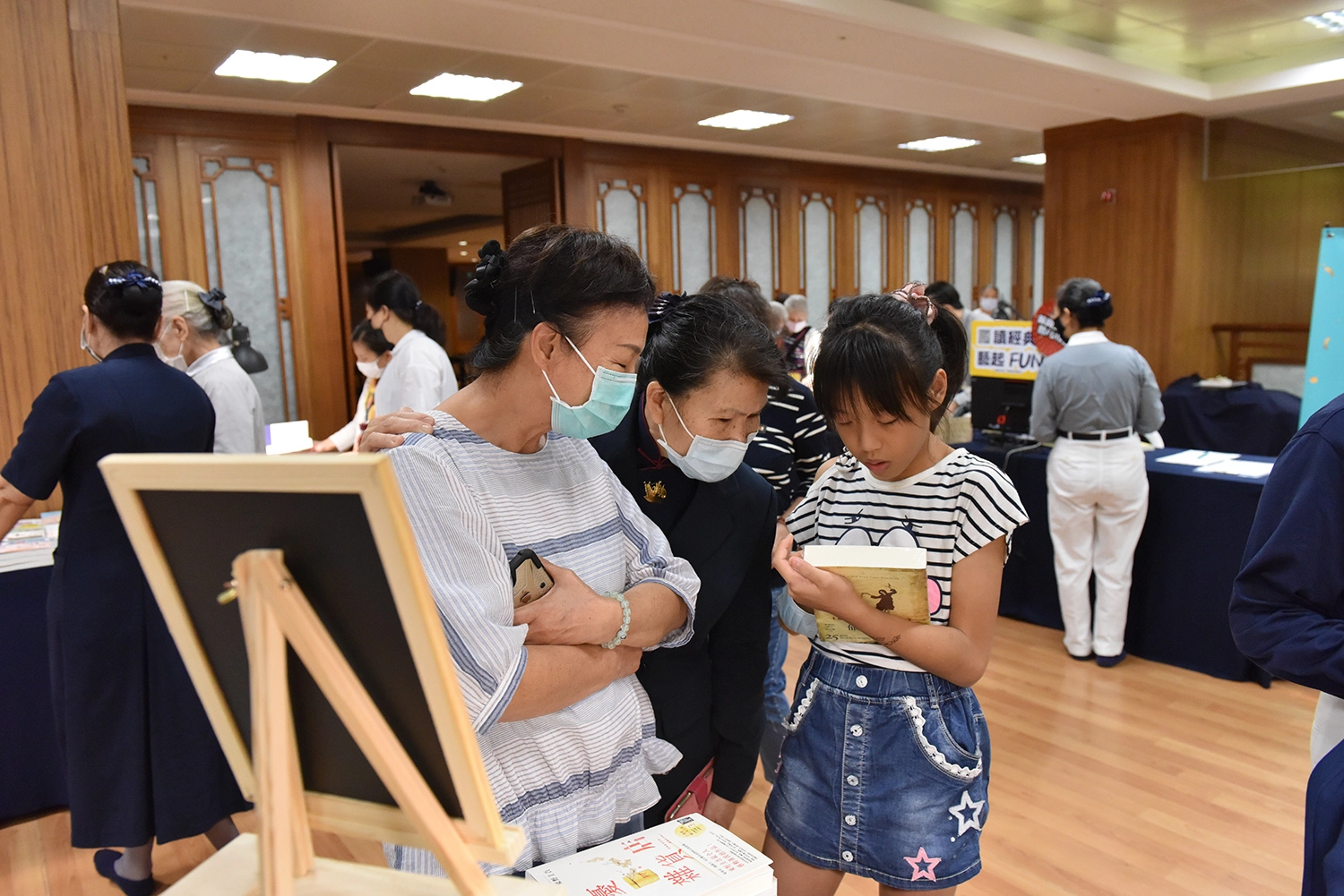 書展現場，親子拿起書本討論。
