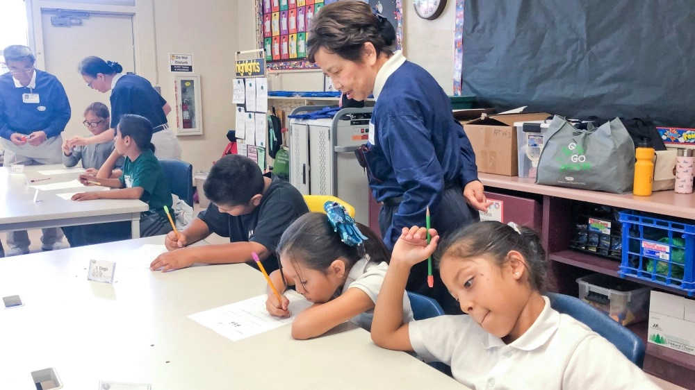 二○一九年加州聖塔安那市麥迪遜小學「幸福校園背包計畫」，透過活動為孩子們進行近距離的引導，聆聽孩子的心聲。呂美力巡著孩子們的學習單。圖／林綺芬提供