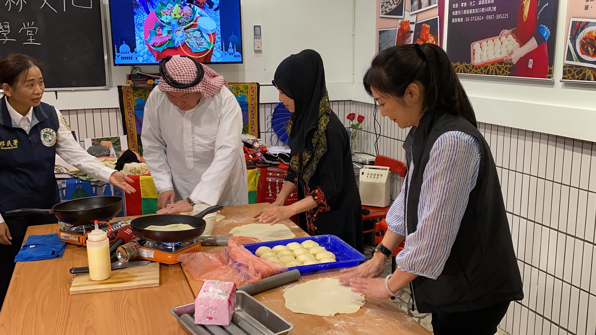 新住民閃淑娟女士(右二)向移民署林主任秘書興春(左二)海基會劉副處長慧玲(右一)及移民署桃園市服務站黃主任英貴(左一)教學手作穆斯林美食-腳後跟餅。