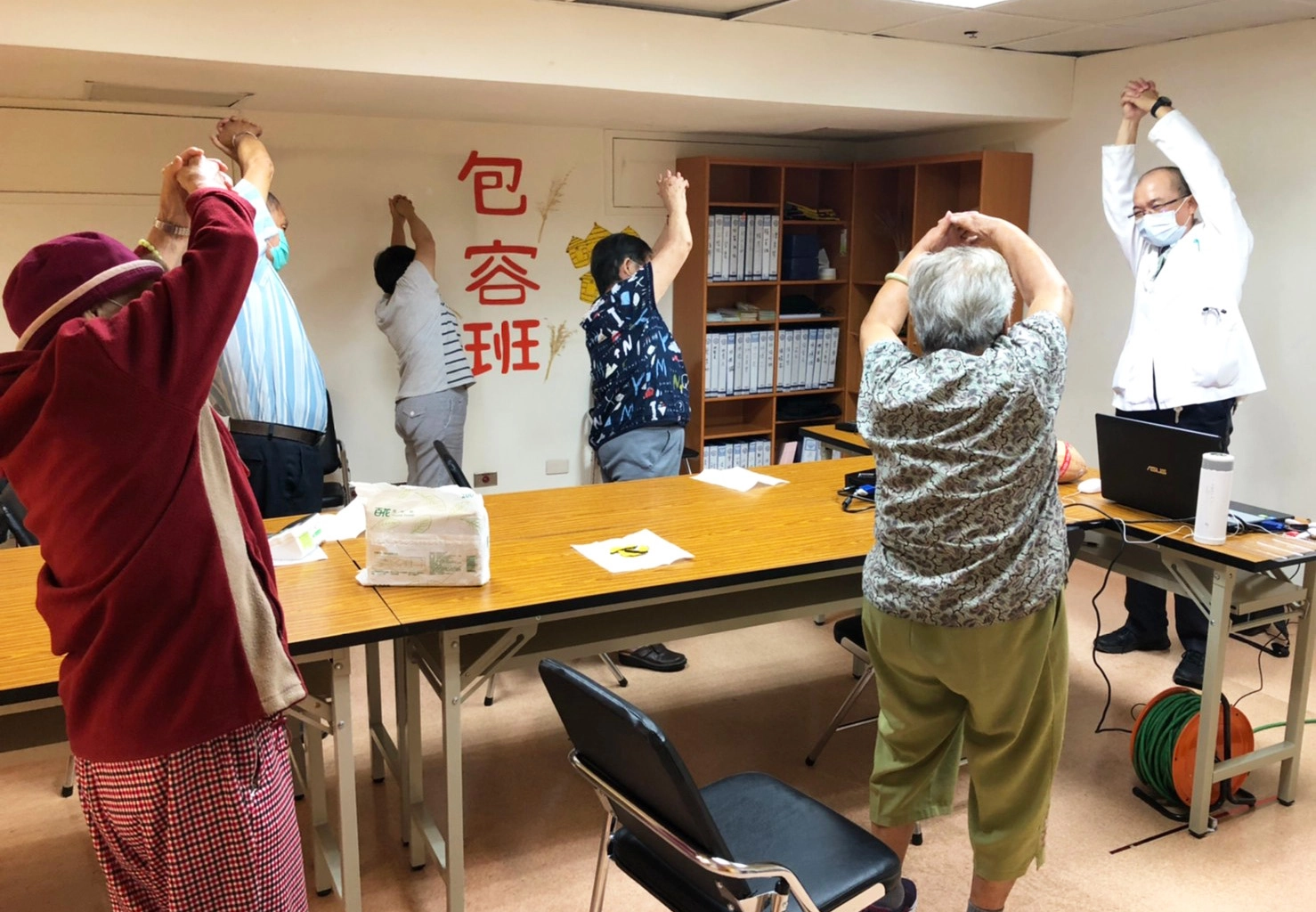 物理治療師林啟文示範帶動頭、上肢、手臂伸展動作，訓練長輩肌肉伸展。
