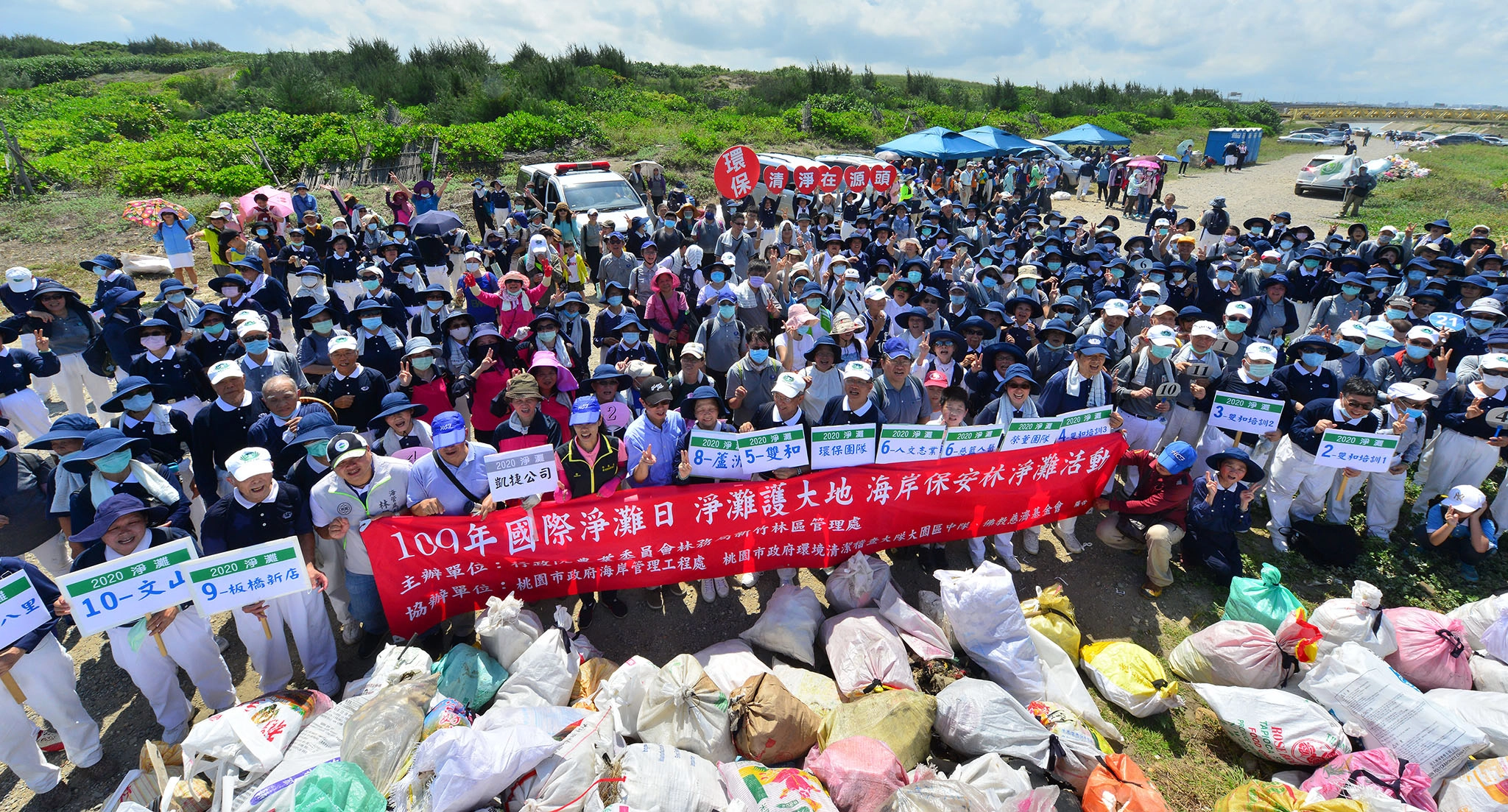 國際淨灘日，全體參與志工與民眾在清出的五千公斤垃圾前，宣示淨灘護大地。