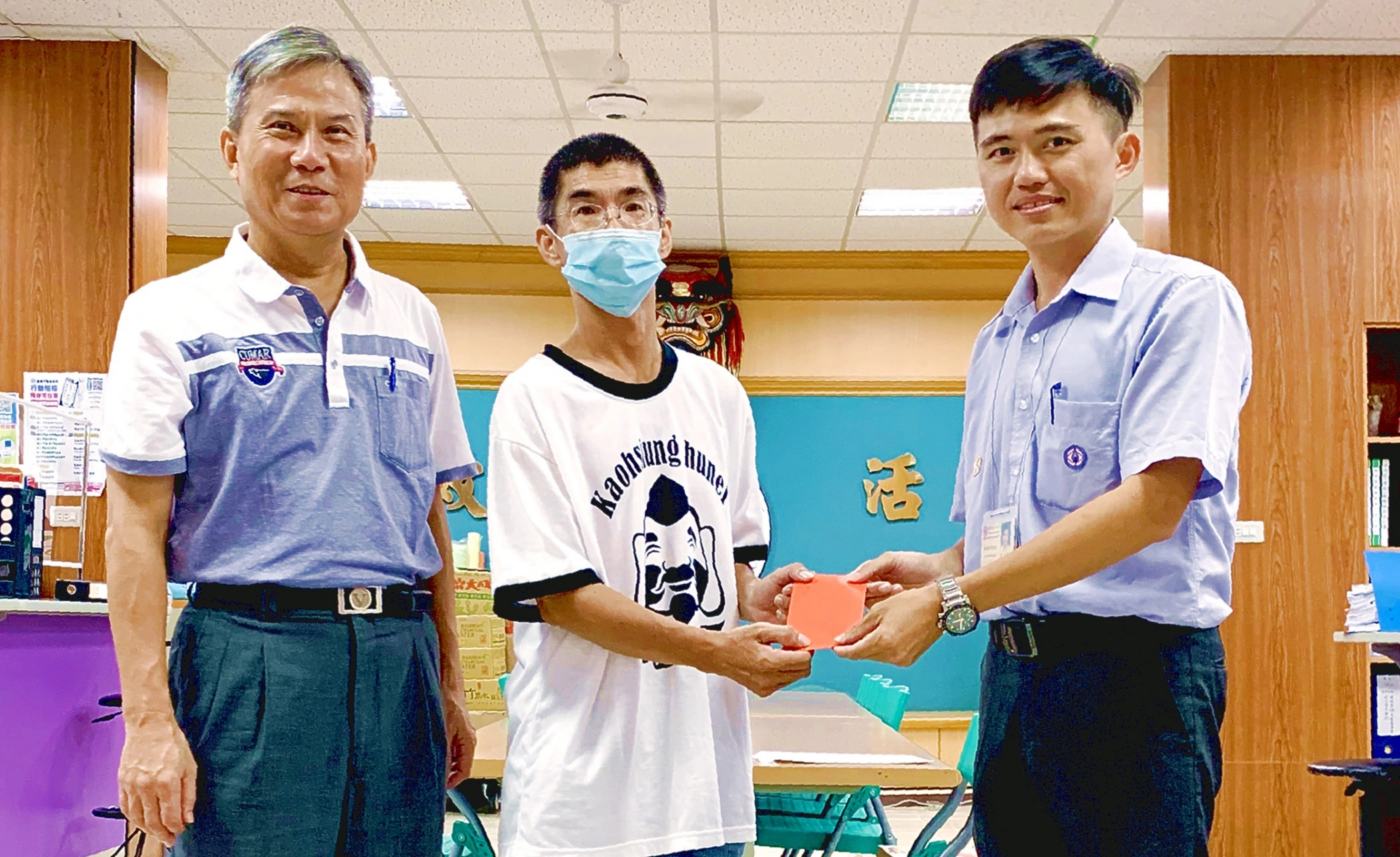台電高雄區處今(25)日由處長李衍新及同仁分頭走訪多間社福機構及在地弱勢民眾。住在高雄湖內的低收入戶阿傑(化名、正中間)在區長薛茂竹(左)見證下，從台電湖內服務所所長莊誌豪(右)手中接過「幸福準備金」，阿傑神情憔悴卻仍難掩激動，不停向台電同仁致謝。