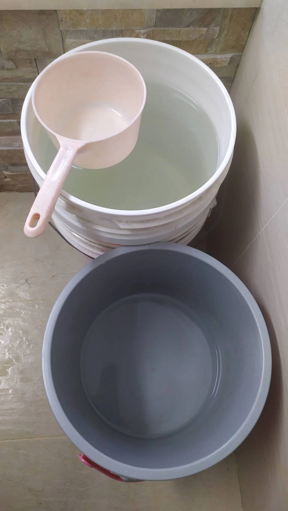 陳姓志工儲存熱水流出前的冷水於水桶，她表示這些水都是乾淨的水質，要珍惜使用。(圖為慈濟基金會提供)