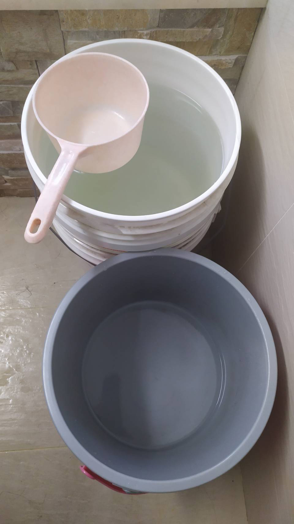 陳姓志工儲存熱水流出前的冷水於水桶,她表示這些水都是乾淨的水質,要珍惜使用。(圖為慈濟基金會提供)