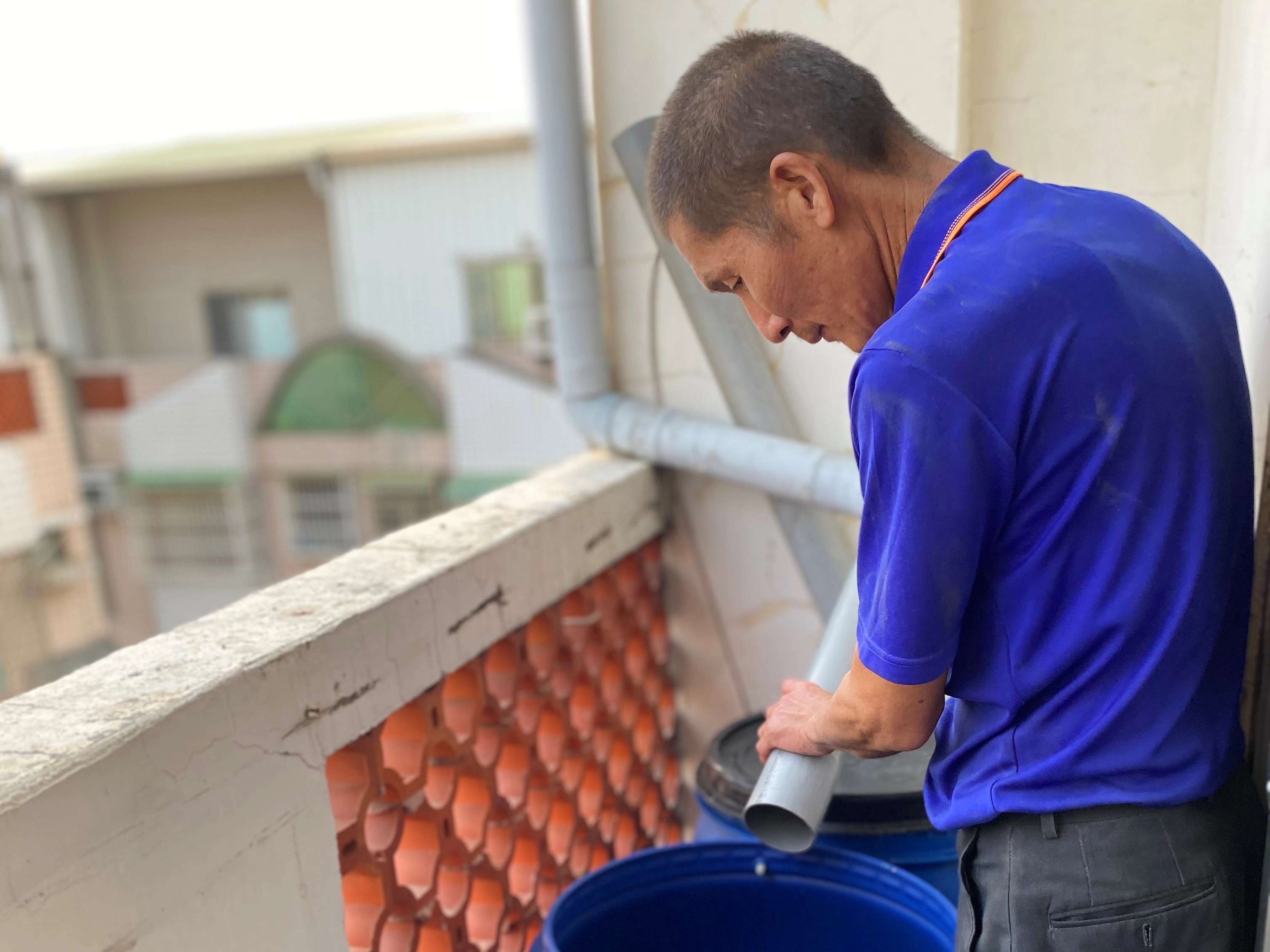 劉素花家用管子將屋簷的雨水接到水桶。(攝影：劉素花)
