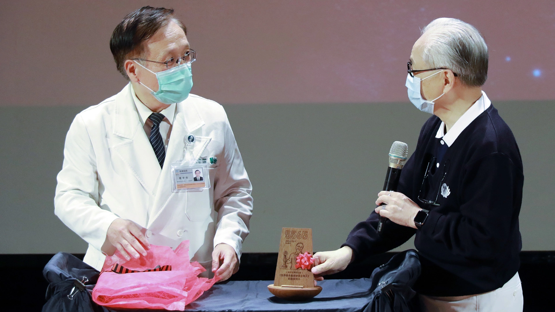慈濟傳播人文志業基金會合心精進長姚仁祿（右）頒發親自設計的「世界最長醫療節目主持人紀錄保持人」獎項給簡守信。