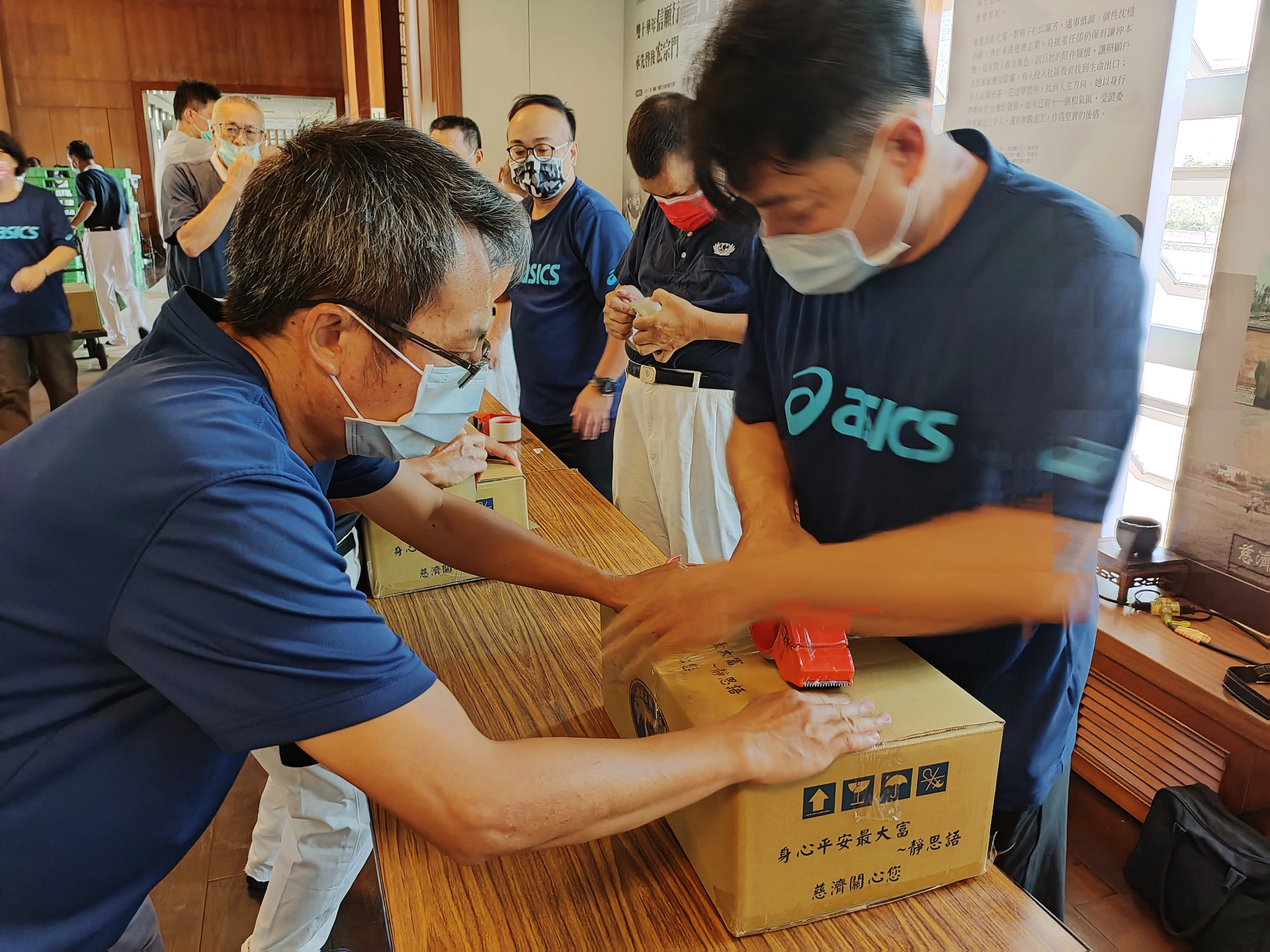 彰化縣教育處卓鴻賓課督(左)與慈濟志工一起打包第二批暑期安心生活箱，過程中感到很歡喜。