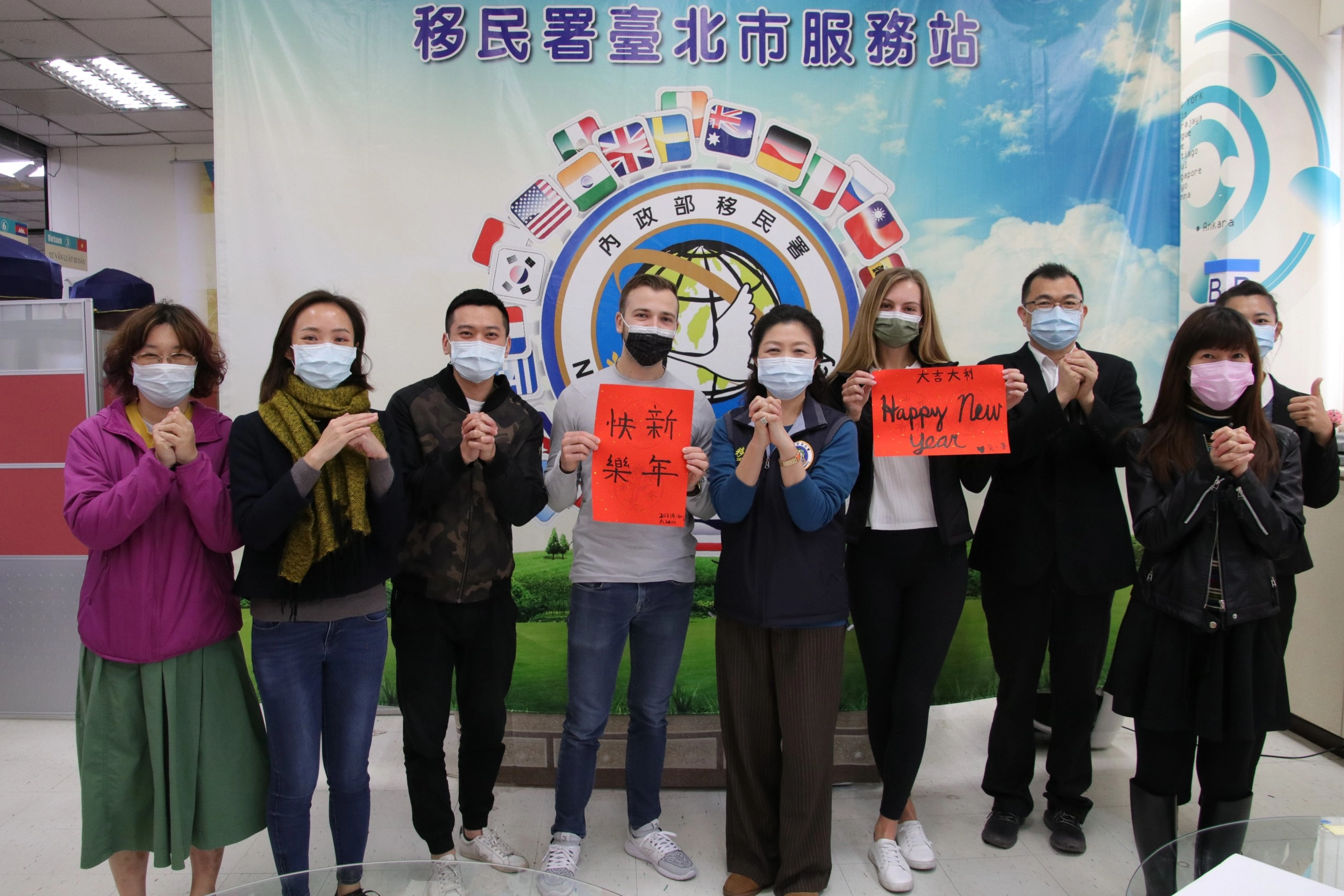 莫彩曦(左六)、Adam(左四)與移民署臺北市服務站視察洪湘鳳(左五)及 同仁一起祝賀「新年快樂」、「Happy New Year」!