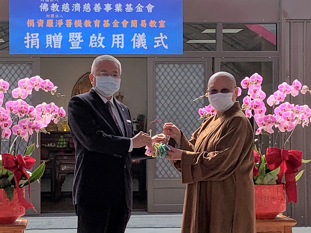 2月24日雲林慈濟志工余天助(左)代表致贈組合教室鑰匙，由印可法師(右)代表領取。