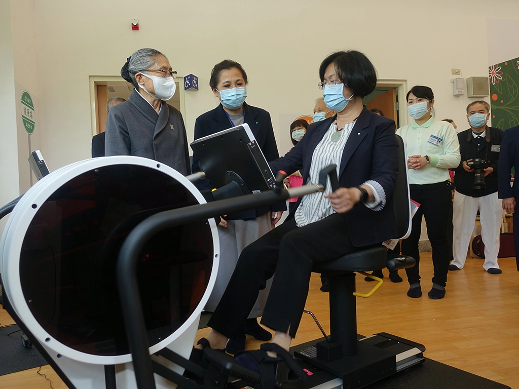彰化縣長王惠美在慈濟長照總召集人林碧玉(左一)、副召集人莊淑婷(左二)陪伴下，體驗日照中心長者的健身器材。