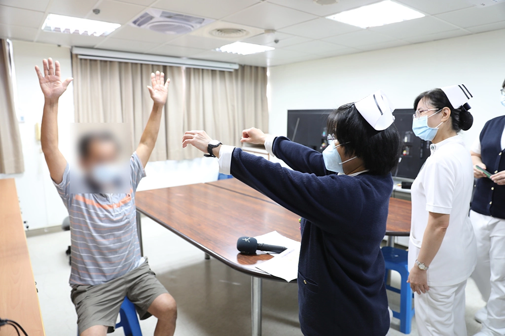 二十東病房護理長張素雯陪唐先生(化名)複習出院後要做的復健動作。
