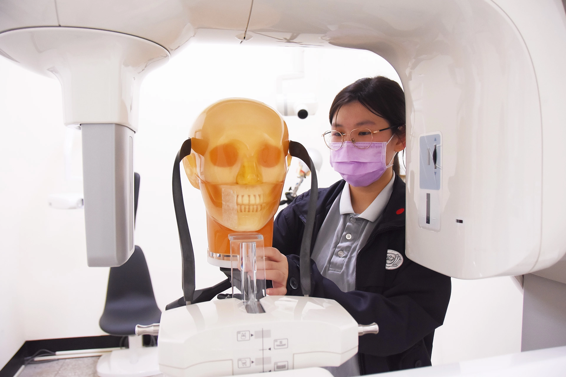 醫放系工讀生調整牙科攝影機器。