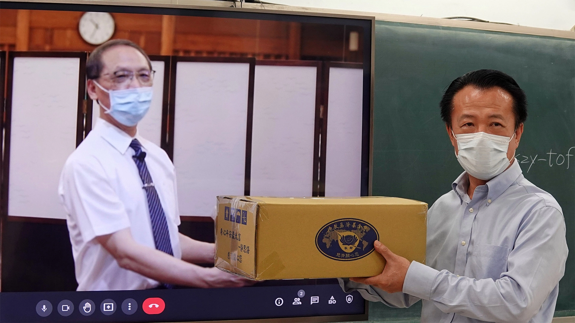 慈濟捐贈嘉義縣政府1500戶弱勢學生家庭暑期安心生活箱、健康蔬果箱，7月15日由慈濟顏博文執行長(左)透過視訊交給翁章梁縣長(右)。