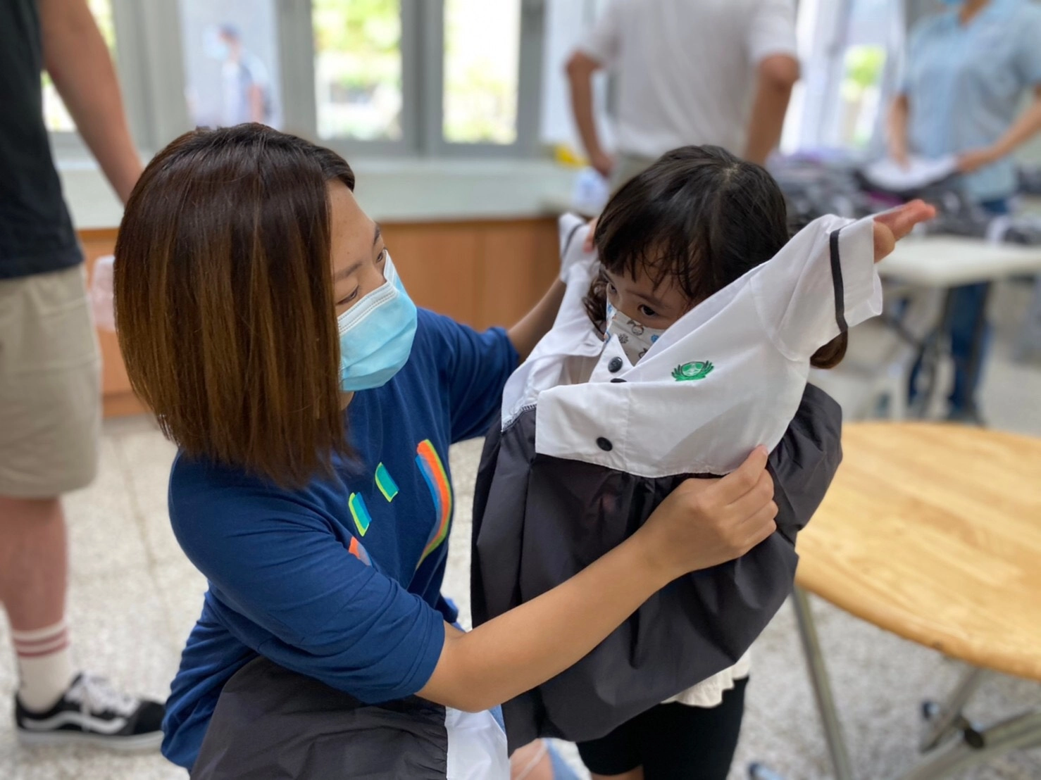 幼兒園新生在家長與老師的協助下，第一次試穿制服，準備迎接人生新階段。攝影：臺南