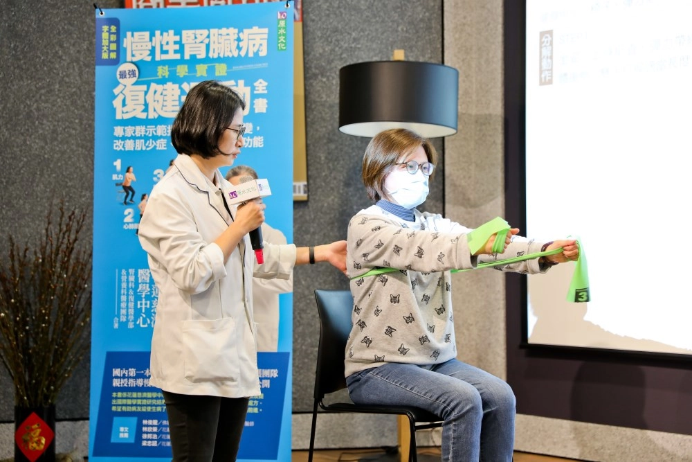 復健醫學部物理治療師黃意雯教導腎友坐著也能強化手及腳部肌力的簡單方法，示範者為張逸真個案管理師。