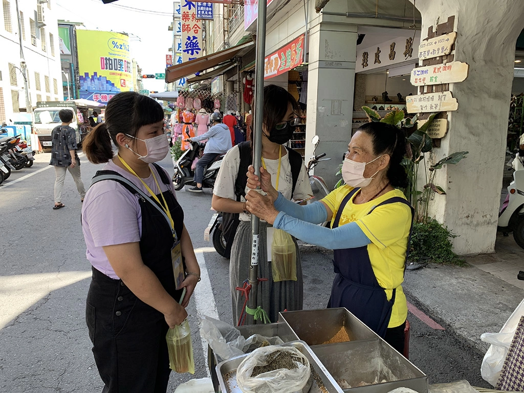 青年志工於屏東中央市場內和老店家採訪互動。