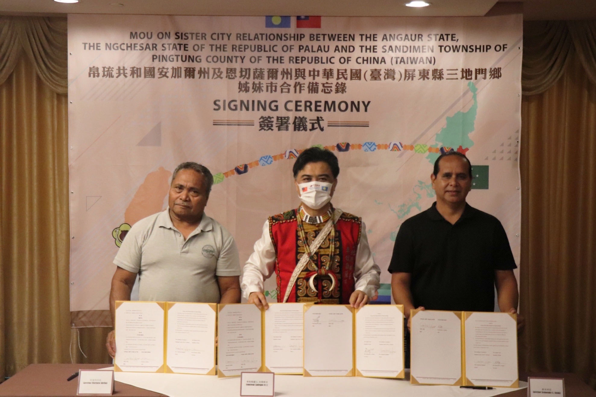 左一恩切薩爾州阿道拜州長（Governor Florencio Adelbai）、左二三地門鄉公所車牧勒薩以．拉勒格安Cemelesai Ljaljegan鄉長、右一安加爾州鈴木州長（Governor Kennosuke A. Suzuky）共同簽署姊妹市合作備忘錄。