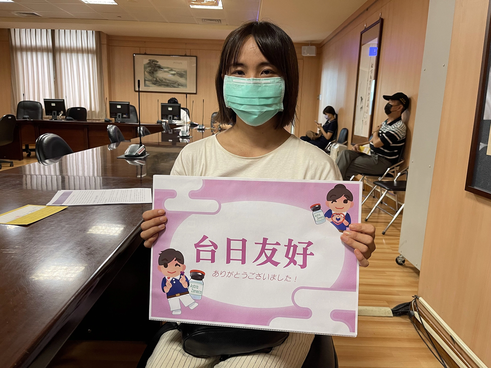 疫苗接種結束，保田女士在休息區手持「台日友好」手板留影。
