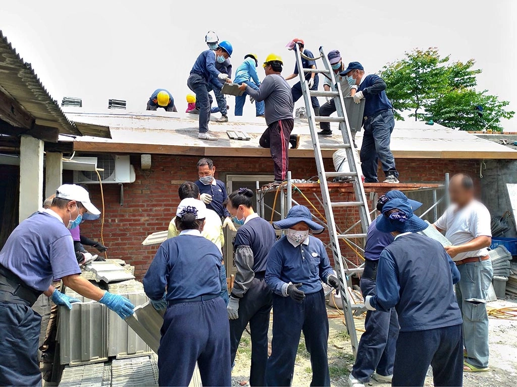 慈濟志工將700多片的新屋瓦以接力方式傳給屋頂 的工班師傅。