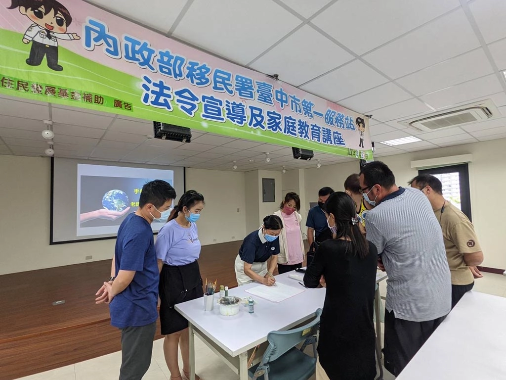 世界地球日移民署響應環保從日常做起，家庭教育活動師姐示範彩繪手帕。