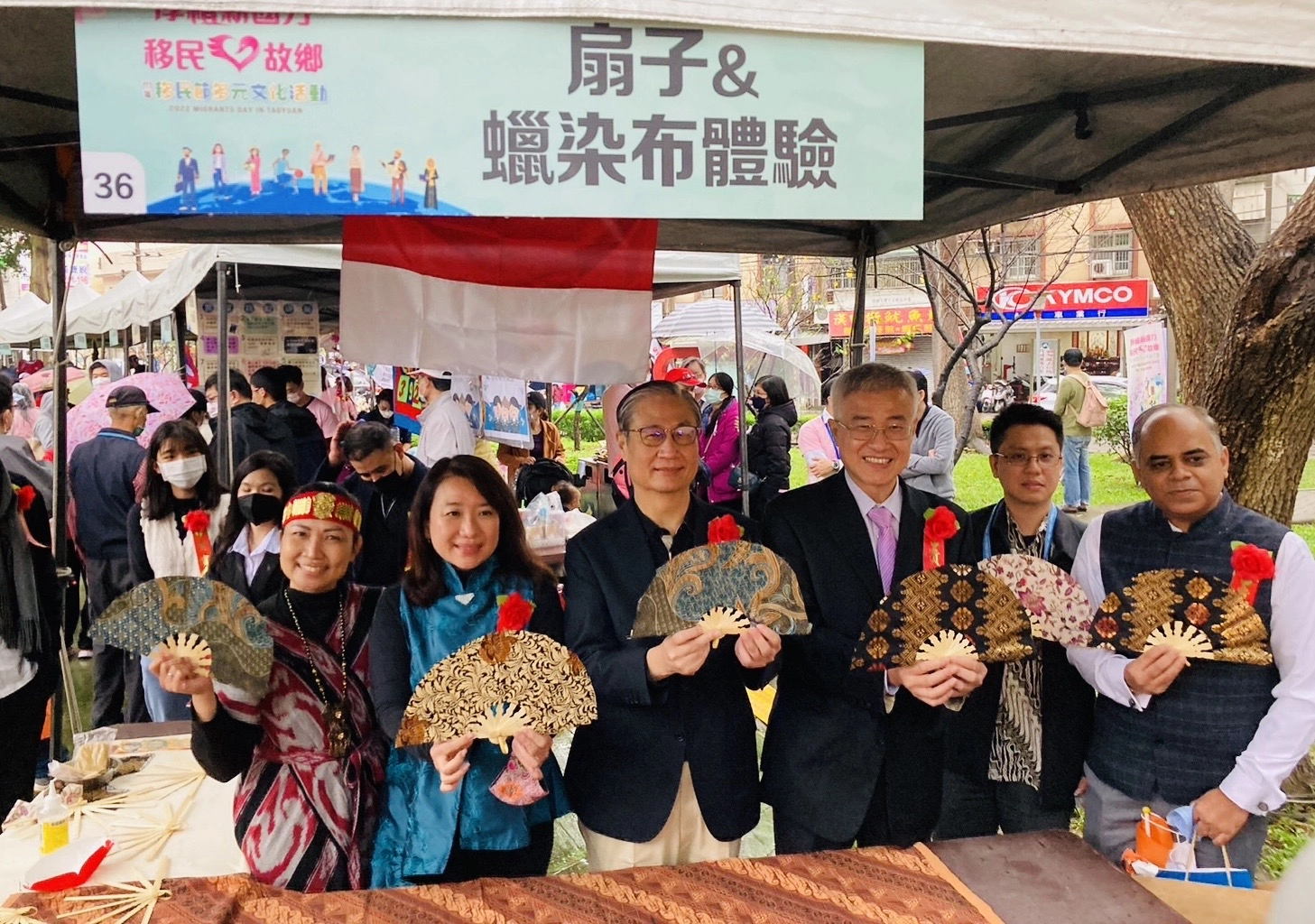 移民署署長鐘景琨(右四）、桃園市副市長李憲明(右三)及印尼代表處郭進來專員一同逛桃園新市集攤位,體驗手作印尼蠟染扇子。